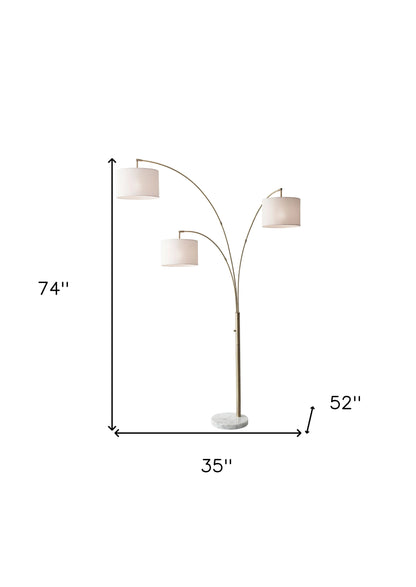 74" Brass Three Light Arc Floor Lamp With Off White Fabric Drum Shade